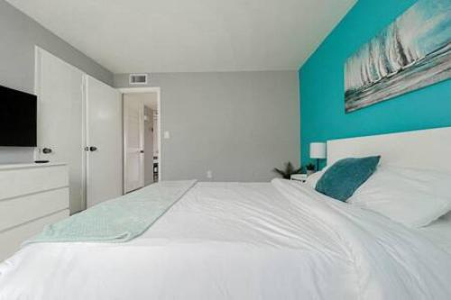 a bedroom with a large white bed with a blue wall at Charming Beach Condo located in Amazing Location! in St Pete Beach