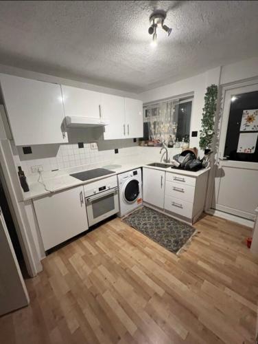 a kitchen with white cabinets and a wooden floor at Spacious Large Modern Double close to Central London Breakfast Included in London