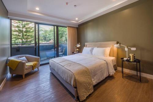 a bedroom with a bed and a chair and a window at El Tesoro Medellín Hab311 by Letoh in Medellín