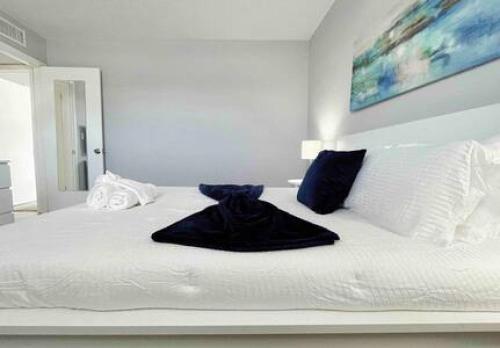 a white bed with a black robe sitting on it at Perfect Beach Getaway with Dock AND Pet Friendly in St Pete Beach