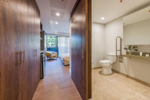 a bathroom with a toilet and a room with a bed at El Tesoro Medellín Hab311 by Letoh in Medellín