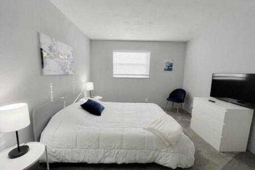 a white bedroom with a bed and a television at 2 Bedroom Beach Condo With Dock AND Walk To Everything in St Pete Beach