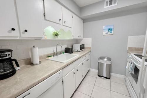 a white kitchen with a sink and a stove at Madeira Beach 2 bedroom Waterfront Condo With Dock in St. Pete Beach