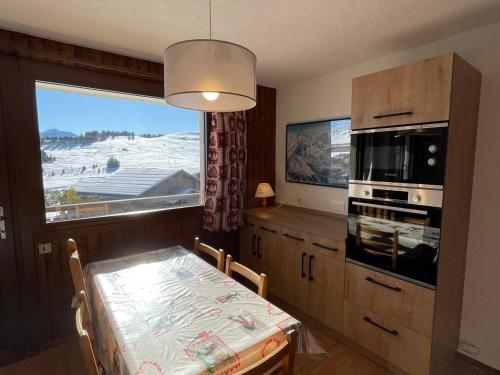 une cuisine avec une table et un four micro-ondes ainsi qu'une fenêtre dans l'établissement Beau studio cabine confortable aux Saisies, Sud, TV, lave-vaisselle, lave-linge - FR-1-293-141, à Hauteluce