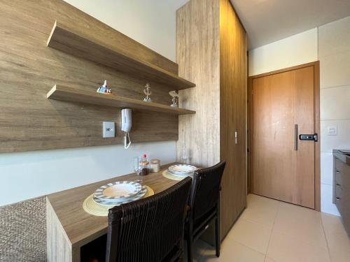 a kitchen with a wooden table and chairs and a door at Makia Flat Muro Alto in Porto De Galinhas