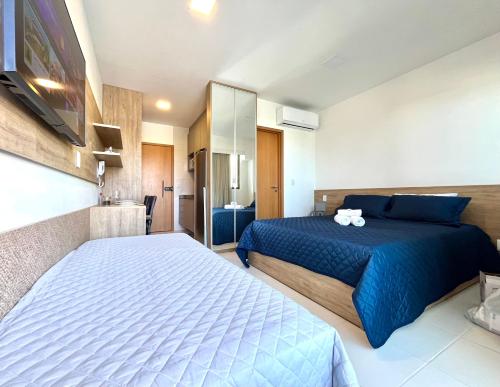 a bedroom with two beds and a tv in it at Makia Flat Muro Alto in Porto De Galinhas