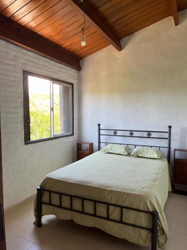 um quarto com uma cama e uma janela em EL CHALÉ casa de campo em Mina Clavero