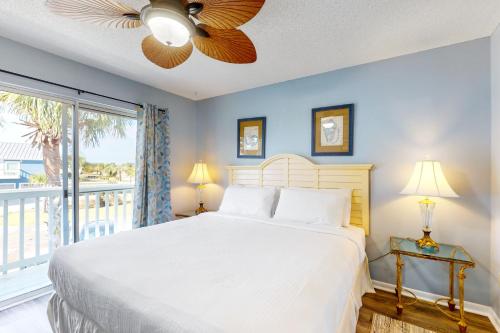 a bedroom with a white bed and a balcony at Healing Hideaway in Saint Joe Beach