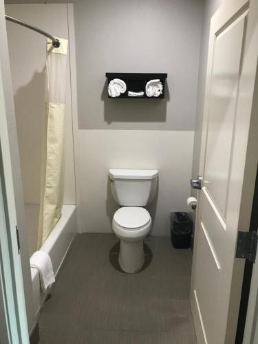 a small bathroom with a toilet and a shower at Grand Villa Inn and Suites Westchase/Chinatown in Houston