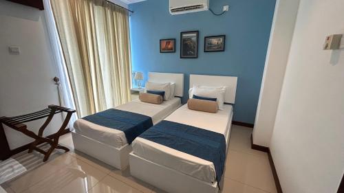 two beds in a room with blue walls at Apartment314 Oceanfront condos Nilaveli in Trincomalee