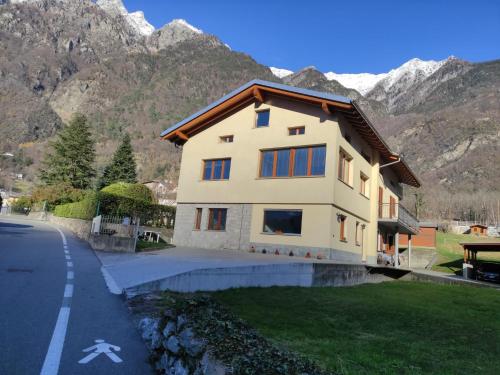 a house on the side of a road with mountains at L'Acero Rosso in Prosto di Piuro