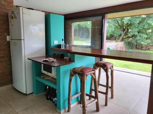 a kitchen with a counter with stools and a refrigerator at Las Pircas 182 in San Salvador de Jujuy