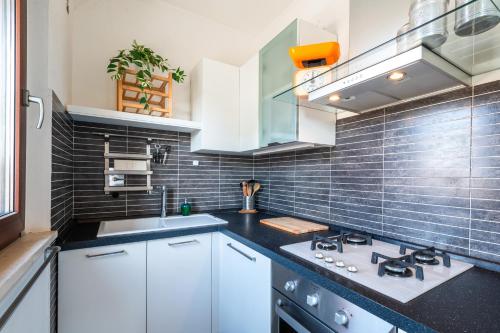 a kitchen with white cabinets and a black tile wall at Home Around in Rome