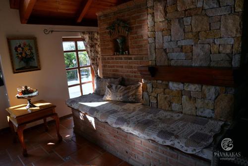 eine Ziegelwand mit einem Bett in einem Zimmer mit einem Fenster in der Unterkunft Pávakakas Vendégház in Vác
