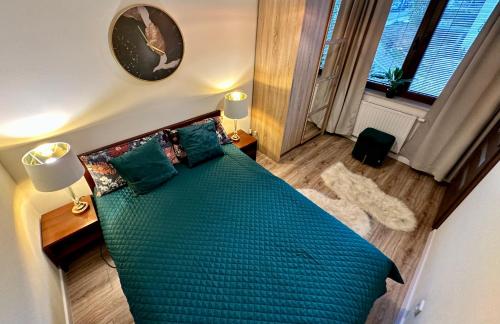 um quarto com uma cama com um cobertor verde e almofadas em Apartament przy Bulwarach em Krynica-Zdrój