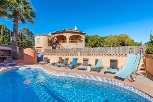 a pool with chairs and a slide in front of a house at Villa Navacerrada - PlusHolidays in Teulada