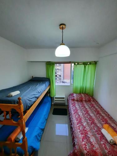 a bedroom with two beds and a window with green curtains at Depto céntrico de 3 habitaciones y cochera in Rosario