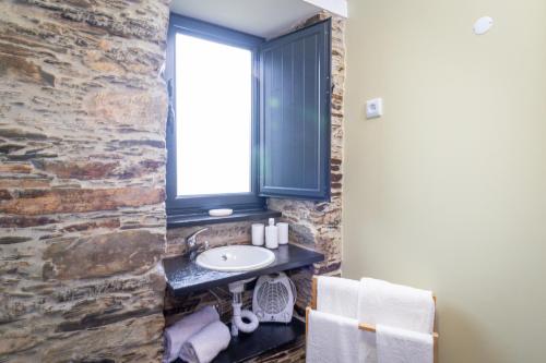 baño con lavabo y pared de piedra en Casa da Professora By ALzira, en Seia