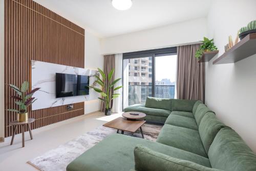 a living room with a green couch and a tv at Fabulous 2BR l High Floor l by Burj Khalifa & Dubai Mall I Pool I Gym in Dubai