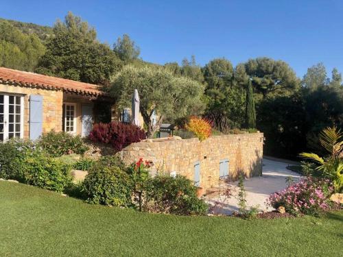une maison avec un mur en pierre dans une cour dans l'établissement Magnifique Maison avec Jardin et Piscine Vue Mer, à Sanary-sur-Mer