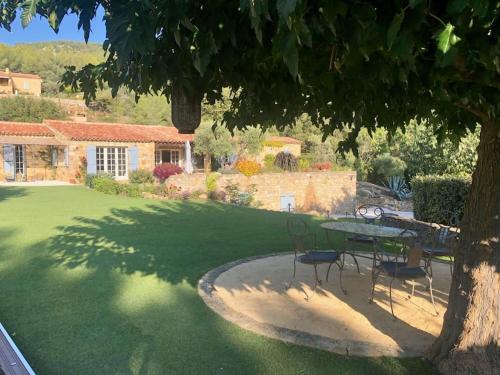 une table et des chaises sous un arbre dans une cour dans l'établissement Magnifique Maison avec Jardin et Piscine Vue Mer, à Sanary-sur-Mer