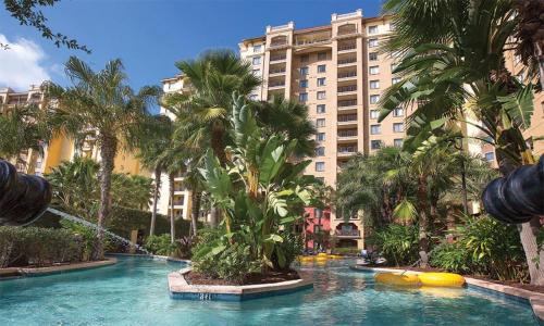 a swimming pool with palm trees in front of a building at Bonnet Creek Resort 1 Bedroom 1 BA Deluxe Villa in Orlando