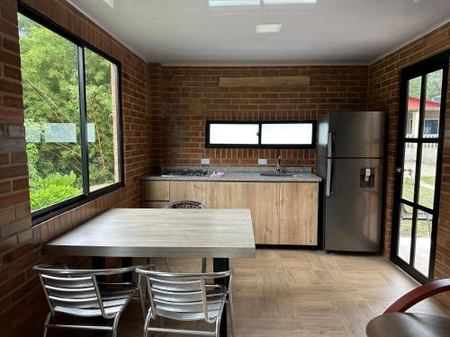 cocina con mesa de madera y nevera en Finca La Primavera - Cabañas Campestres de Descanso, en Sasaima