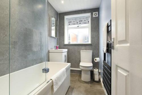 łazienka z wanną, toaletą i oknem w obiekcie New 2 bed home with off-road parking sleeps 6 w mieście Brockhurst