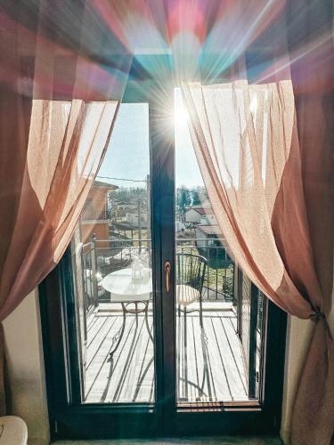 a door with curtains open to a balcony with a table at Filimon GuestHouse Villa in Xanthi