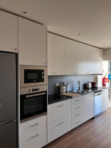 a white kitchen with white cabinets and appliances at Arouca Guest House 2 in Arouca