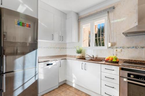 a kitchen with white cabinets and a stainless steel refrigerator at Villa Navacerrada - PlusHolidays in Teulada
