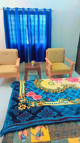 a living room with two chairs and a rug at laxmihomestay in Khajurāho
