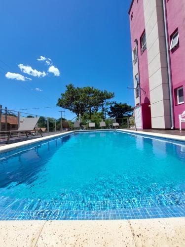 una piscina frente a un edificio rosa en La Ramona Bed & Breakfast en Valeria del Mar