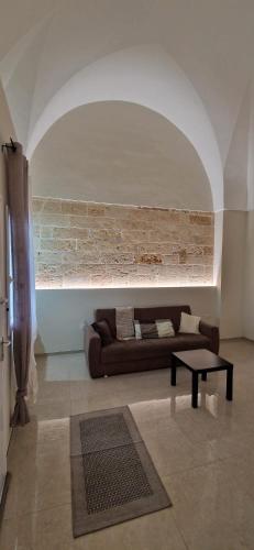 a living room with a couch and a brick wall at Xenia Boutique Apartment in Trepuzzi