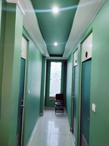 einen Flur mit grünen Wänden und einem Stuhl in einem Zimmer in der Unterkunft Hotel silver spoon and restaurant bhadra in Bhādra