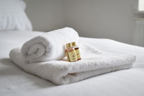 een witte handdoek met een fles essentiële olie op een bed bij Spacious 2 Bedroom Flat with Parking in Portsmouth