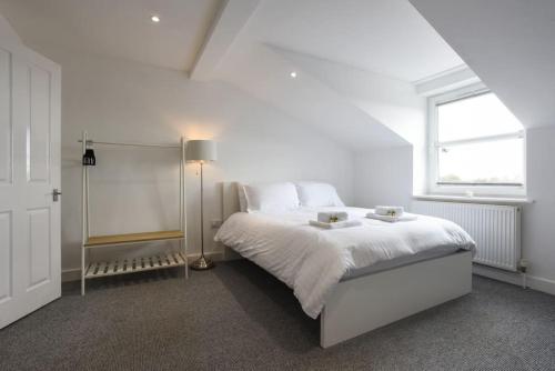 een witte slaapkamer met een bed en een raam bij Spacious 2 Bedroom Flat with Parking in Portsmouth