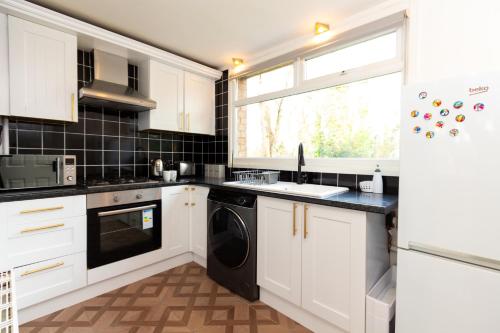 cocina con armarios blancos y lavavajillas negro en Elegant 1Bed Apt near City Centre, en Birmingham