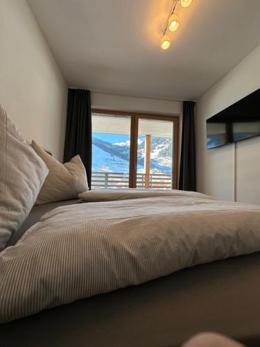 a bedroom with a large bed with a large window at Sonnseit 21 in Grossarl