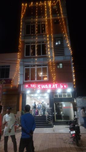 un homme debout devant un bâtiment éclairé dans l'établissement Hotel Swarat Inn By BookingCare, à Amarpātan
