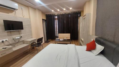 Cette chambre comprend un grand lit et une télévision. dans l'établissement Hotel Swarat Inn By BookingCare, à Amarpātan
