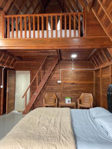 a bedroom with a large bed in a room with wooden walls at "Sakinah" Homestay Syariah AC in Sarilamak