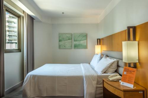 a hotel room with a bed and a table with a phone at Xtay Privilege Botafogo - Apartamentos a 6min da praia e próximo a Copacabana in Rio de Janeiro
