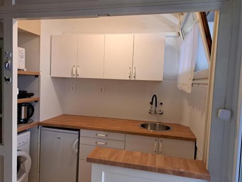 una pequeña cocina con armarios blancos y fregadero en Szoba kilátással apartman, en Gárdony
