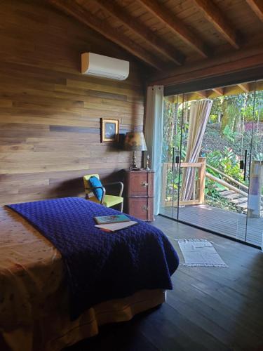 a bedroom with a bed and a sliding glass door at Chalés Paris in Paraty