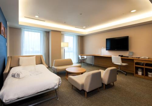 沼津市にあるダイワロイネットホテル ぬまづのベッド1台、薄型テレビが備わるホテルルームです。