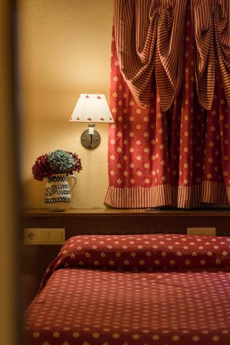 a bedroom with a bed and a lamp and a window at Hotel Aran La Abuela in Vielha