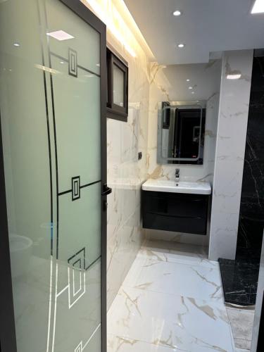ein Bad mit einer Duschtür und einem Waschbecken in der Unterkunft Ferienwohnung mit Meerblick in Al Hoceïma