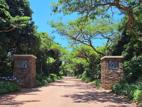 a dirt road with two brick barriers on the sides at Private Garden Room in Zimbali Estate in Ballito
