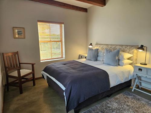 a bedroom with a bed and a chair and a window at Lowergroen Guestfarm, Working Farm in Swellendam